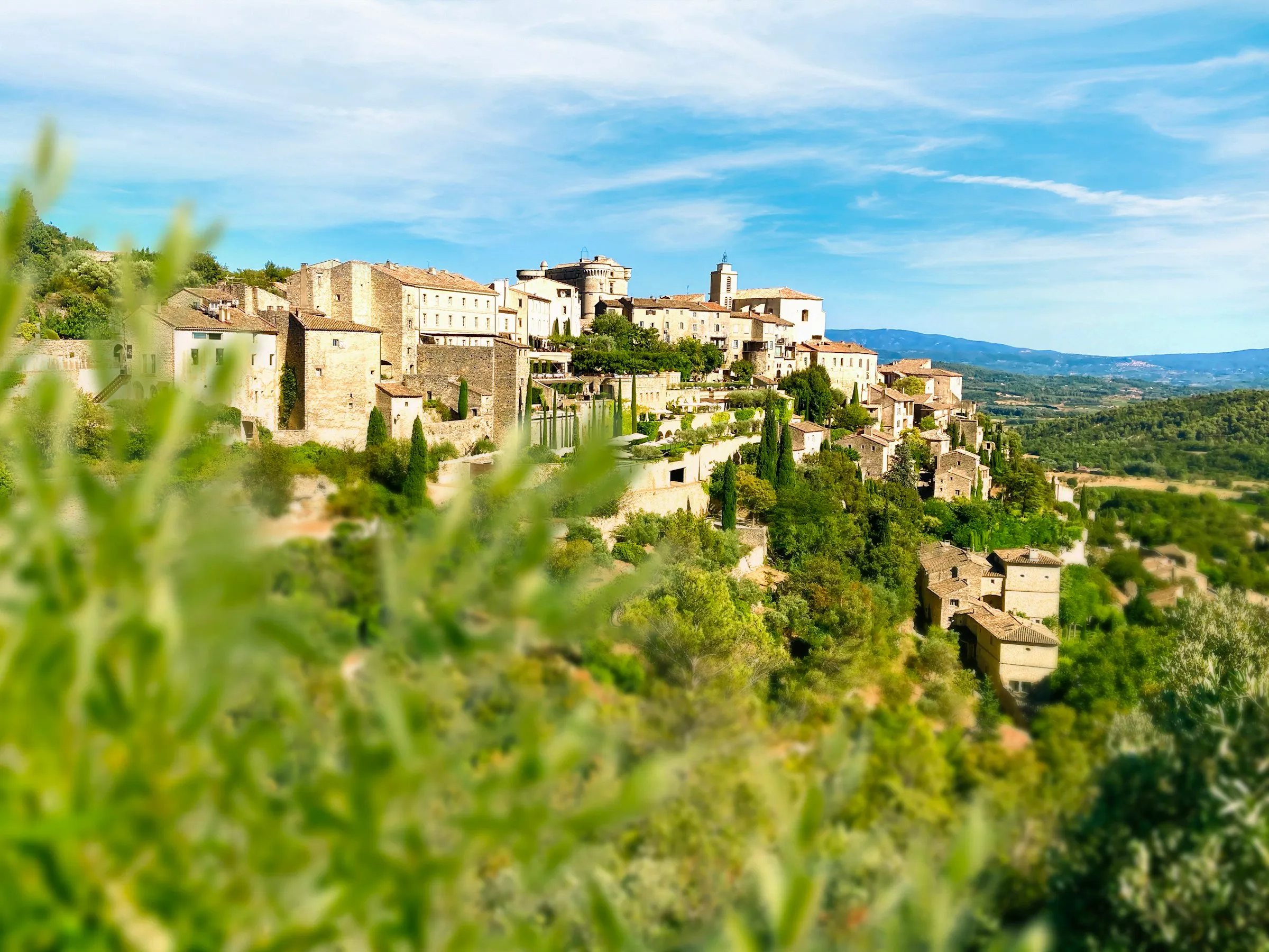 Bourg perché de l'arrière-pays méditerranéen, vu à travers des oliviers.